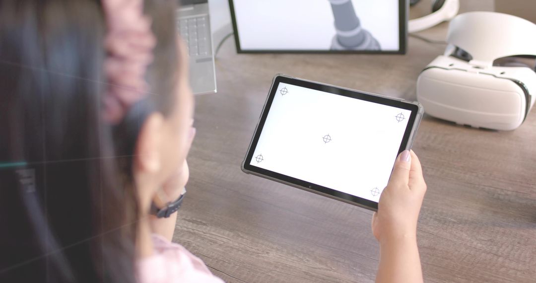 Asian Woman Using Tablet with VR Headset on Desk in Home Office