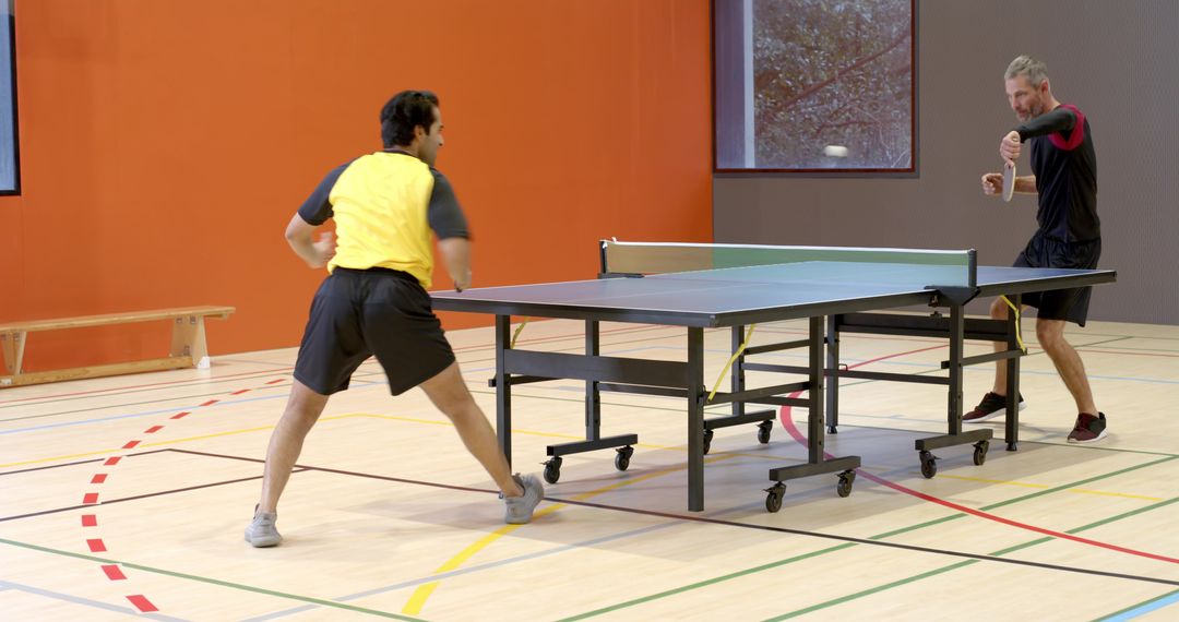 Enthusiastic Table Tennis Match in Gym Setting