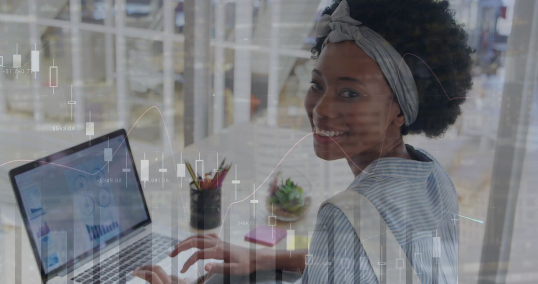 African American Woman Analyzing Financial Data on Laptop with Graph Overlays
