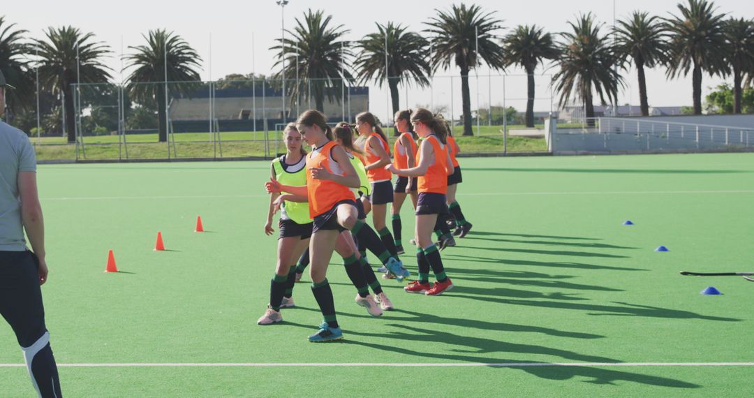 Young women in neon vests practicing field hockey techniques with coach outdoors - Free Images, Stock Photos and Pictures on Pikwizard.com