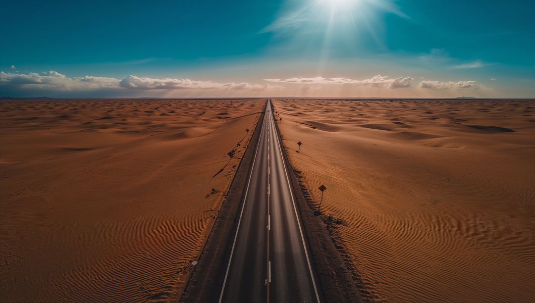 Stretching straight highway cutting through sunlit desert dunes toward distant horizon