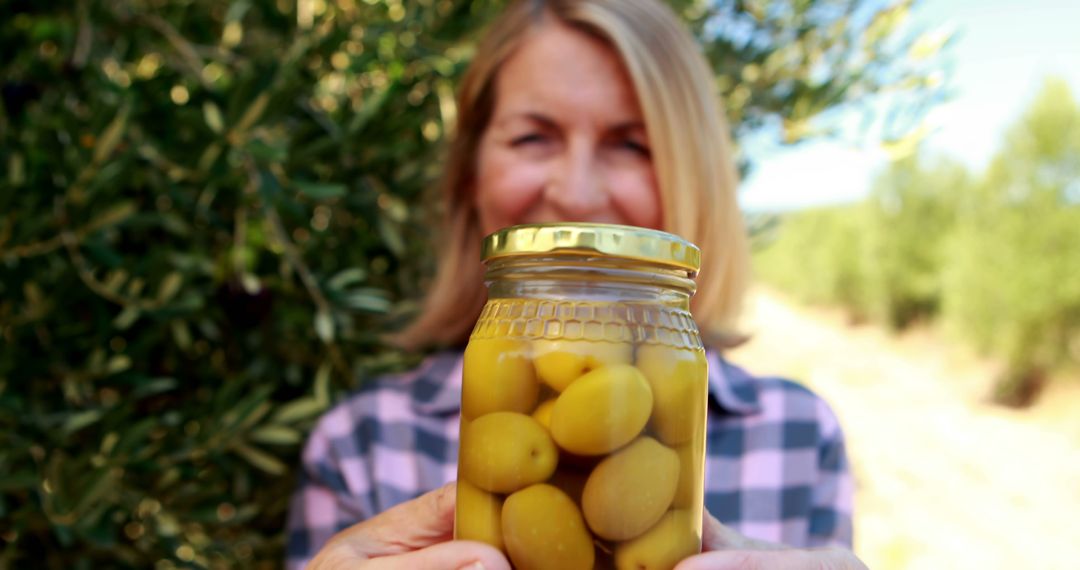 Woman Displaying Freshly Preserved Olives with Pride