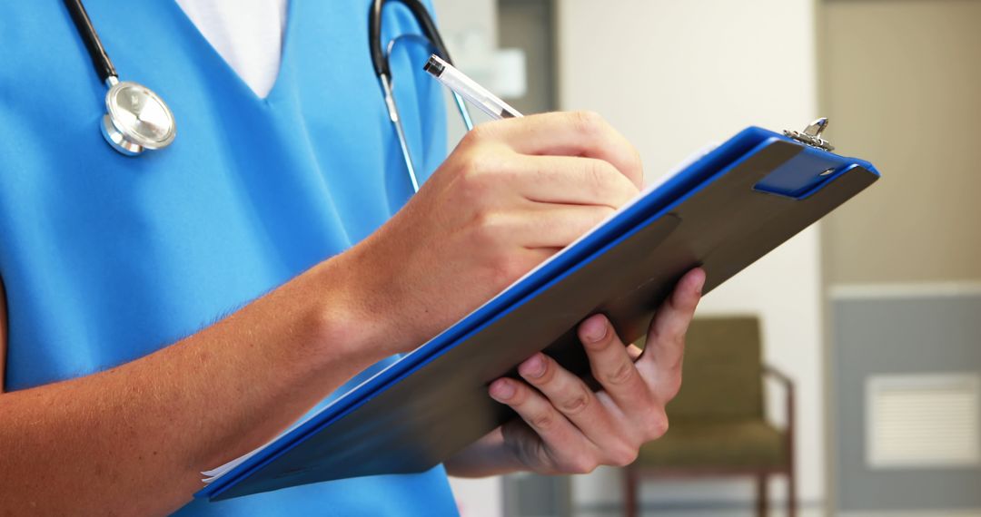 Healthcare Professional in Blue Scrubs Writing on Clipboard - Free Images, Stock Photos and Pictures on Pikwizard.com