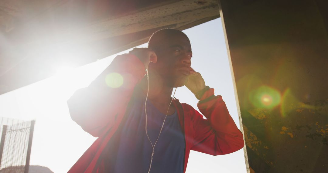 Man Preparing for Workout with Headphones in Morning Sunlight - Free Images, Stock Photos and Pictures on Pikwizard.com