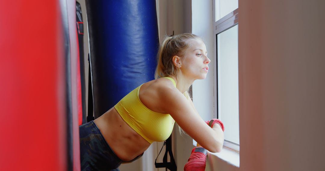 Focused Athlete Resting During Boxing Workout at Gym Window