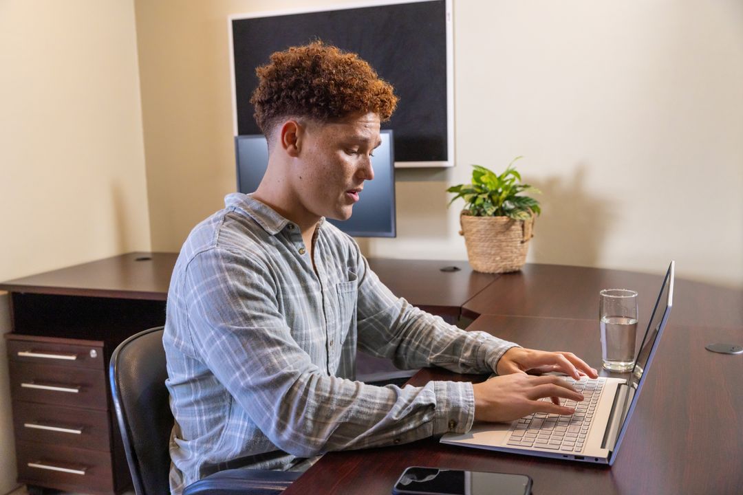 Focused Professional Working on Laptop at Modern Office Desk