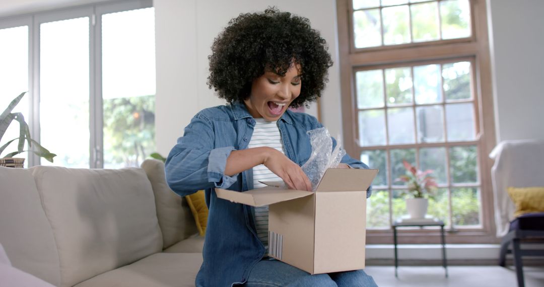 Excited Woman Opening Delivery Package in Living Room - Free Images, Stock Photos and Pictures on Pikwizard.com