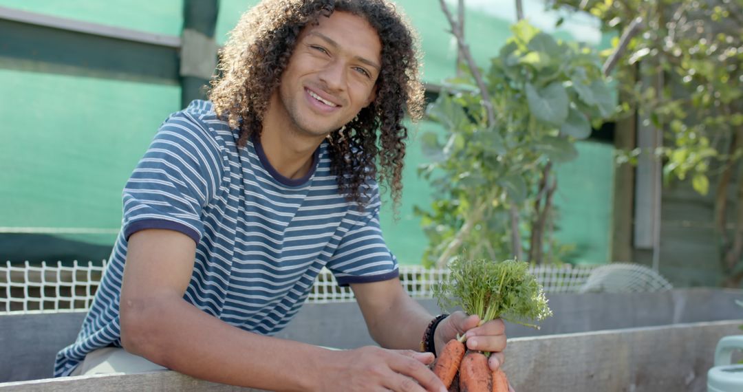 Young Man Smiling While Harvesting Fresh Carrots in Community Garden - Free Images, Stock Photos and Pictures on Pikwizard.com