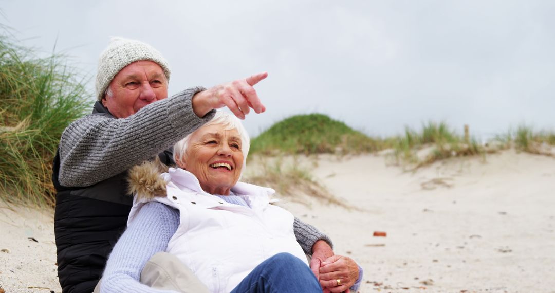 Senior Couple Enjoying Day at Beach Pointing at Horizon - Free Images, Stock Photos and Pictures on Pikwizard.com