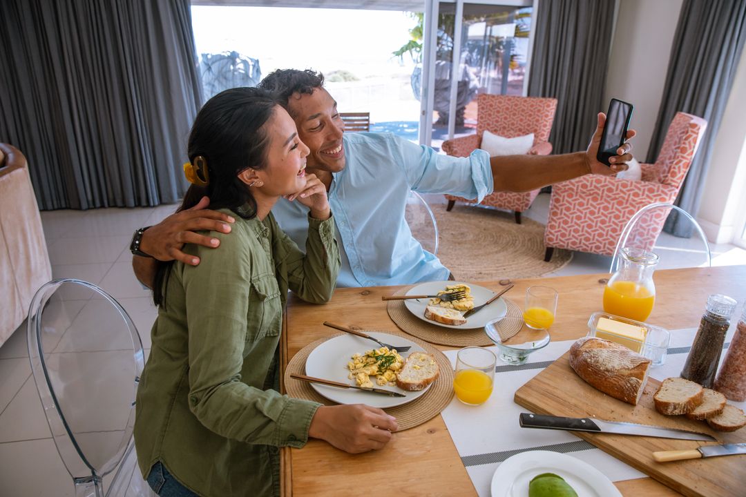 Diverse Couple Taking Selfie at Breakfast Table in Bright Home