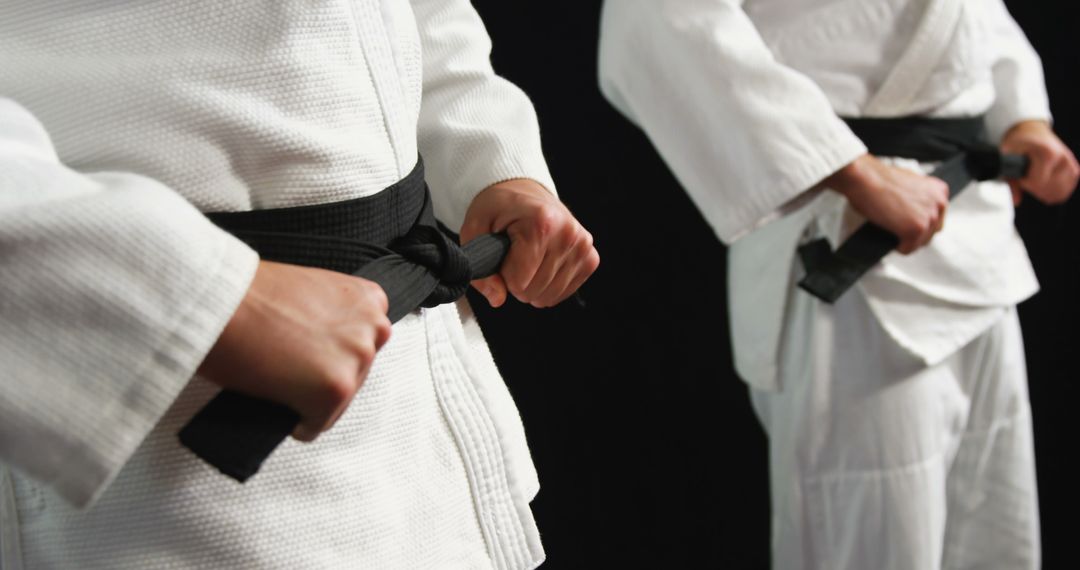 Martial Arts Students Tying Black Belts in Uniforms During Training - Free Images, Stock Photos and Pictures on Pikwizard.com