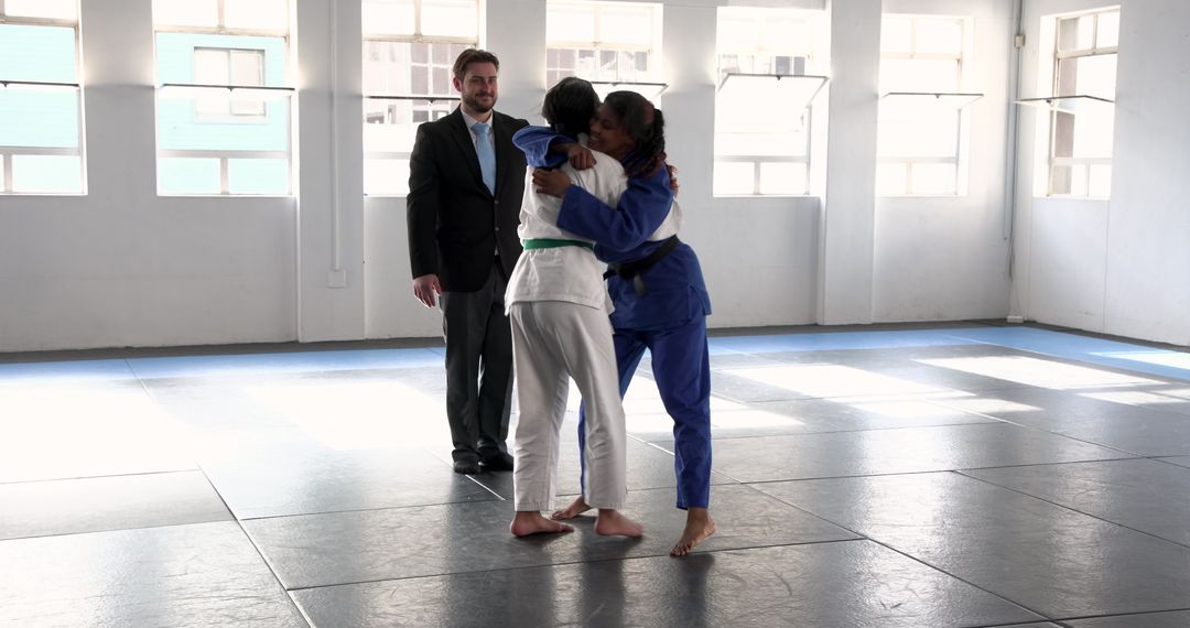 Teenage Girls Practicing Judo with Instructor in Sunlit Dojo