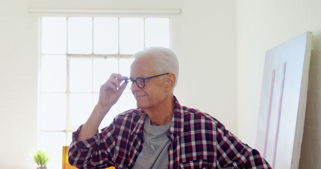 Senior Man Adjusting Glasses In Bright Living Room - Free Images, Stock Photos and Pictures on Pikwizard.com