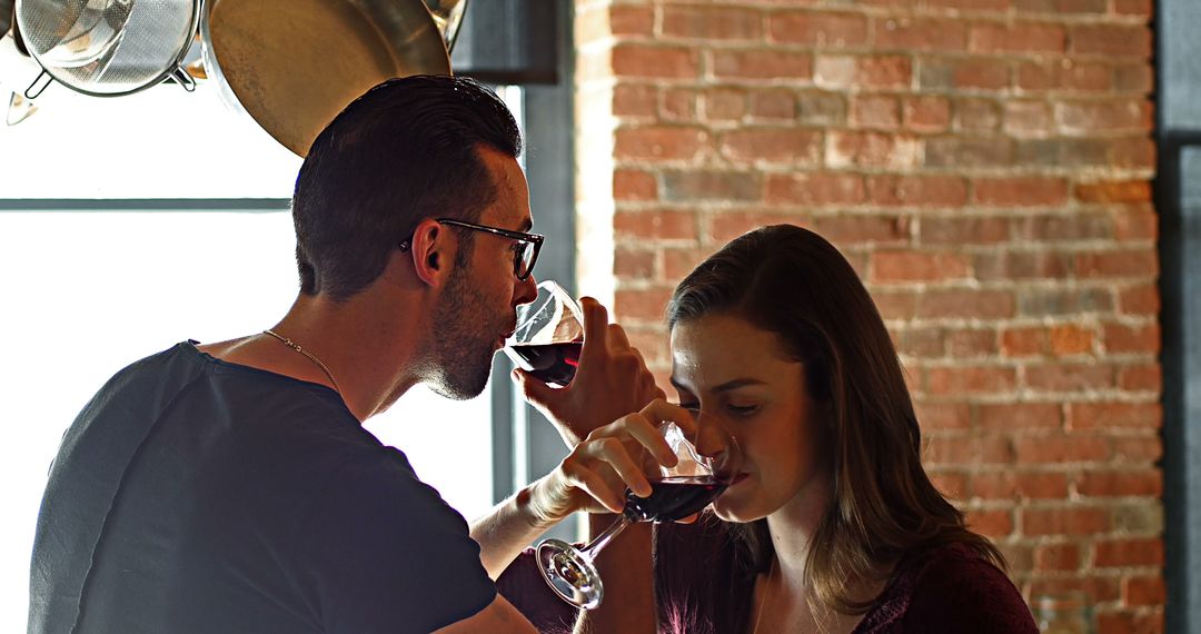 Young couple enjoying red wine in industrial kitchen - Free Images, Stock Photos and Pictures on Pikwizard.com