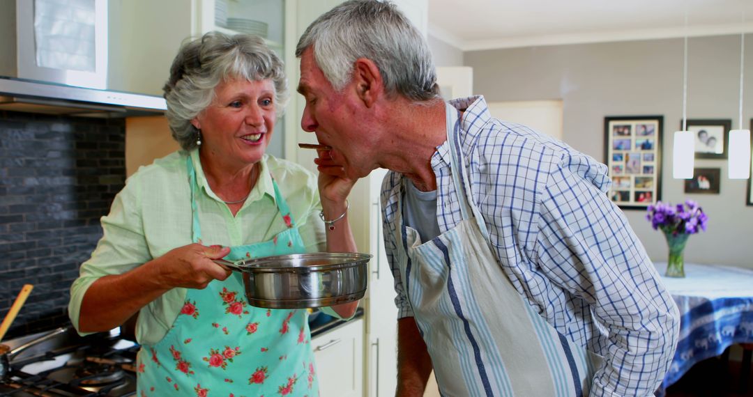 Senior couple cooking together in kitchen, tasting food - Free Images, Stock Photos and Pictures on Pikwizard.com