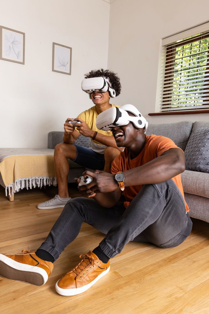 Diverse male friends playing virtual reality game at home with wireless controllers