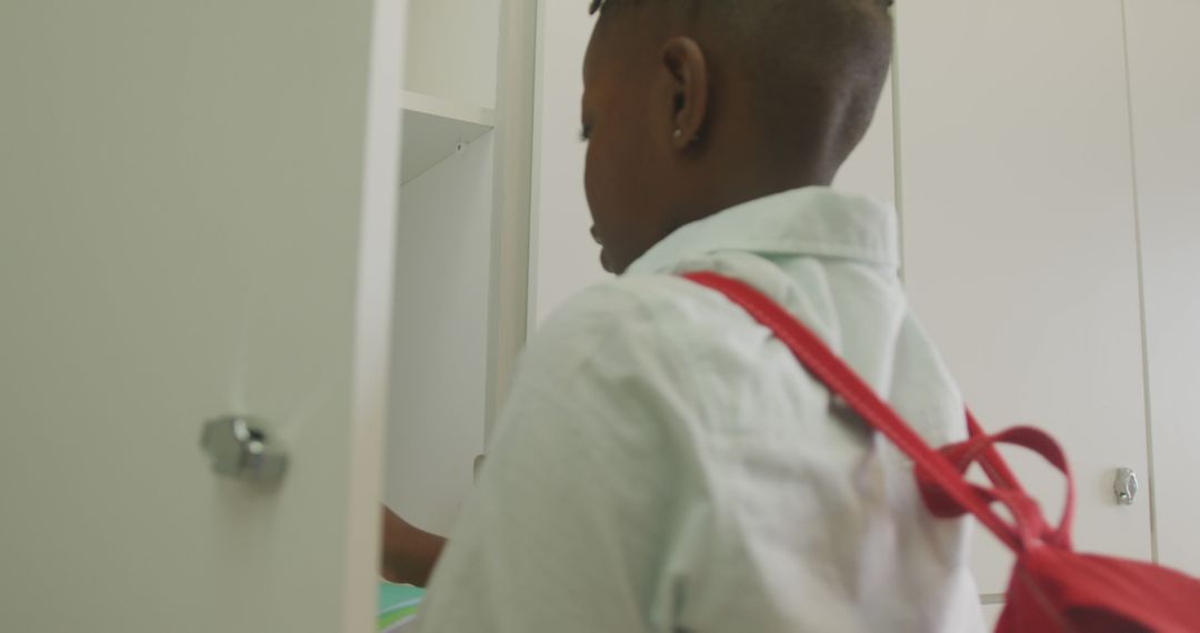 Schoolboy With Red Backpack Closing Locker in Classroom