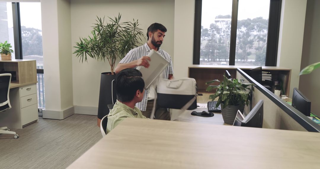 Colleagues Collaborating With Laptop and Bag in Modern Office