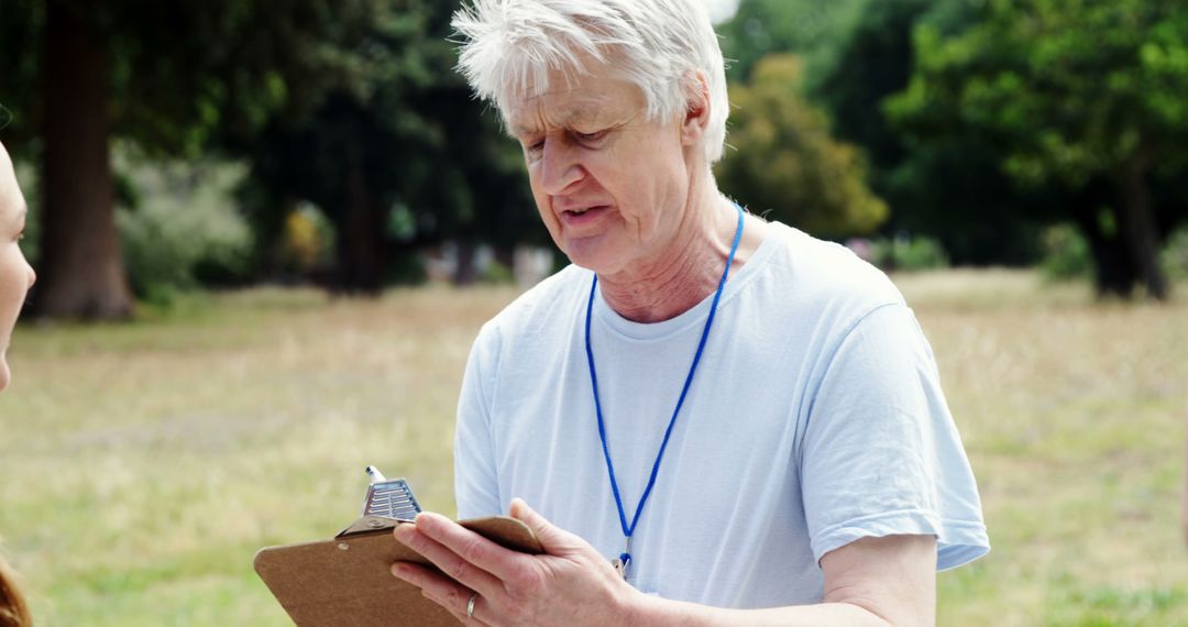 A senior man attentively interacts with a clipboard-wielding person at an outdoor event. - Free Images, Stock Photos and Pictures on Pikwizard.com
