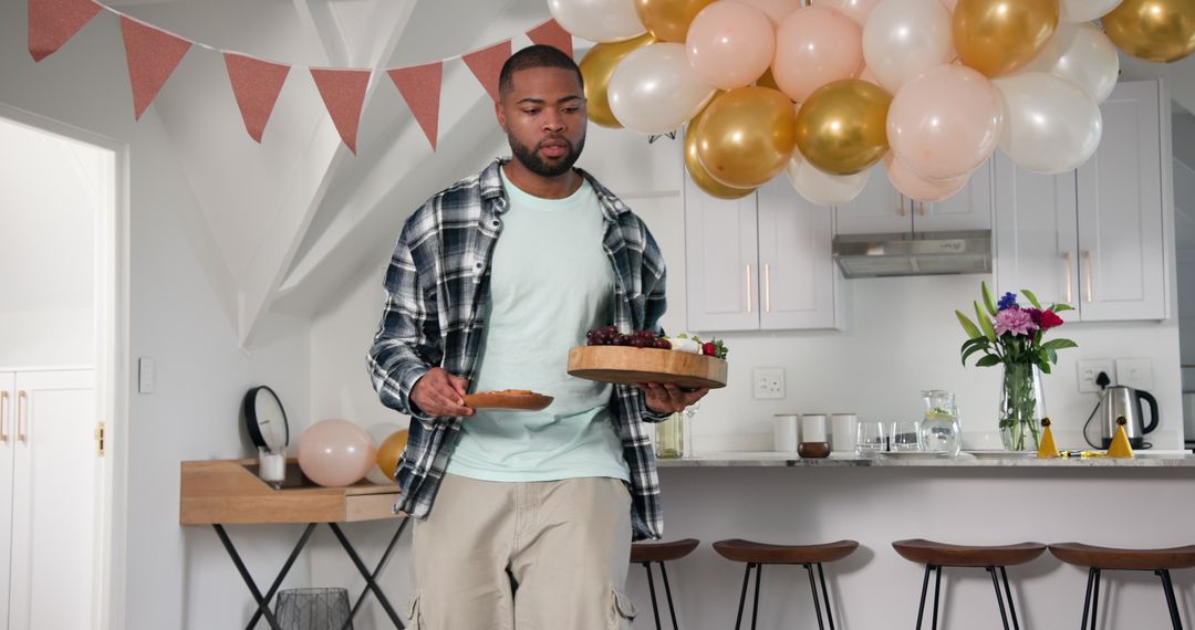 Man Preparing Anniversary Party with Balloons and Snacks at Home
