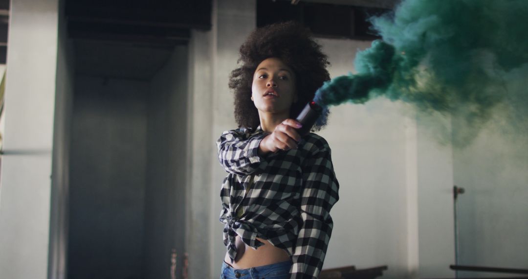 Confident Woman Holding Green Smoke Bomb in Industrial Space - Free Images, Stock Photos and Pictures on Pikwizard.com