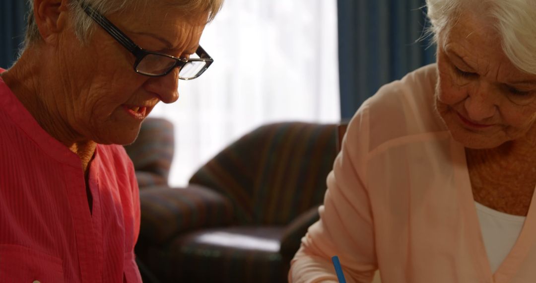 Elderly Women Sharing a Moment with Book and Pen - Free Images, Stock Photos and Pictures on Pikwizard.com