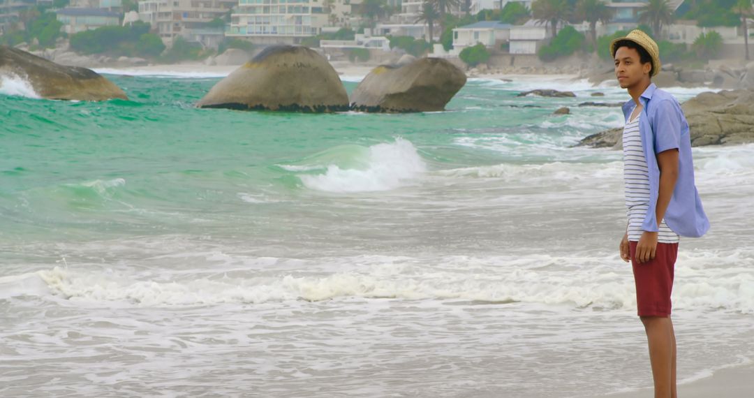 Contemplative Man in Summer Attire Standing by Ocean Waves