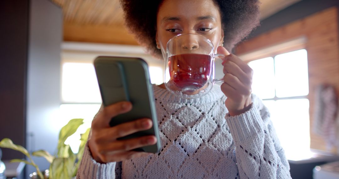 Woman Drinking Tea and Using Smartphone in Cozy Home Setting - Free Images, Stock Photos and Pictures on Pikwizard.com