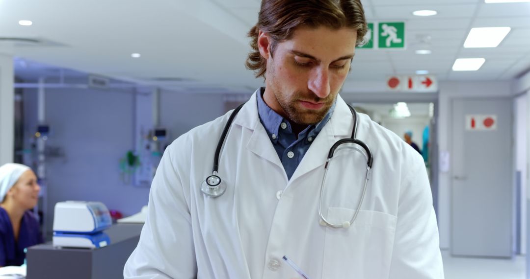 Male Doctor Reviewing Medical Notes in Hospital Corridor - Free Images, Stock Photos and Pictures on Pikwizard.com