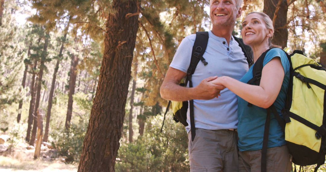 Two Hikers Smiling and Holding Hands While Hiking in a Forest
