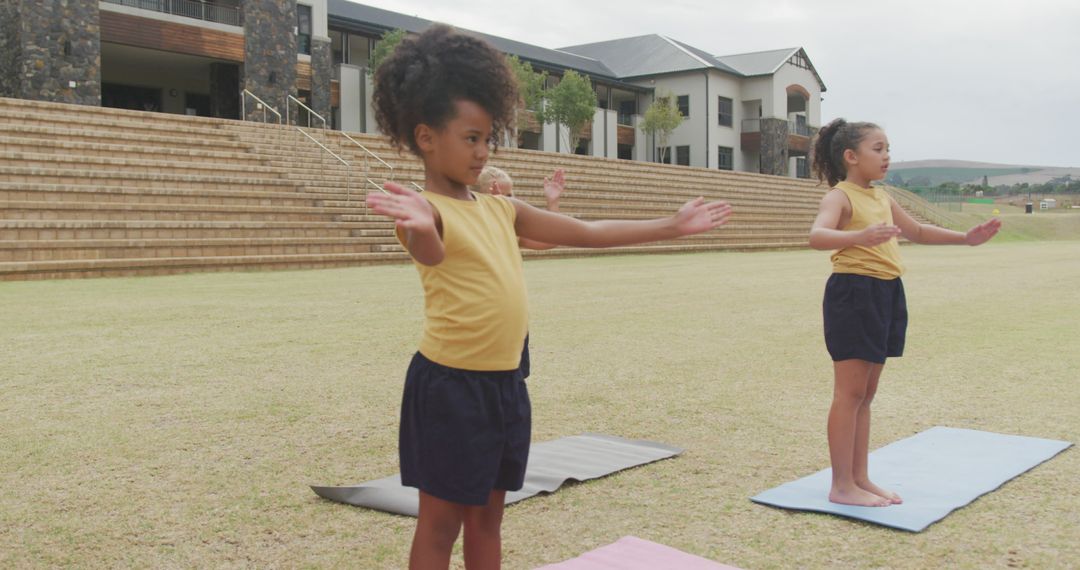 Image of focused diverse girls practicing yoga on mats in front of school - Free Images, Stock Photos and Pictures on Pikwizard.com