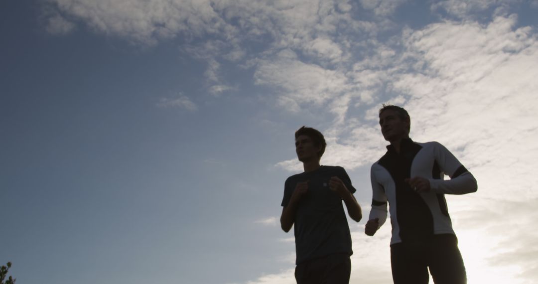 Silhouette of Two Men Jogging at Dawn Under Cloudy Sky - Free Images, Stock Photos and Pictures on Pikwizard.com