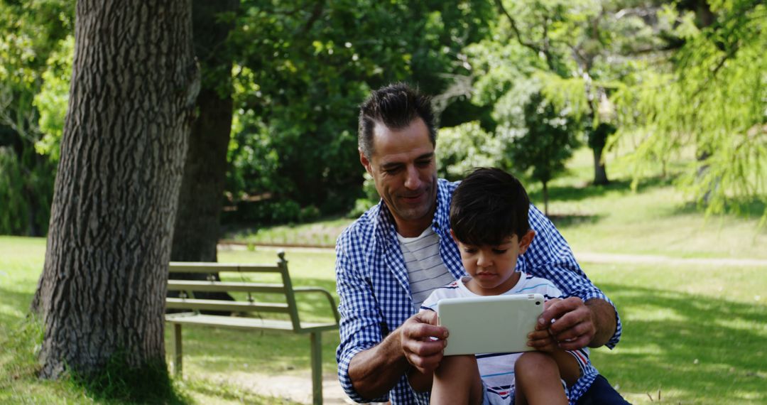 Father and Son Using Digital Tablet in Park - Free Images, Stock Photos and Pictures on Pikwizard.com