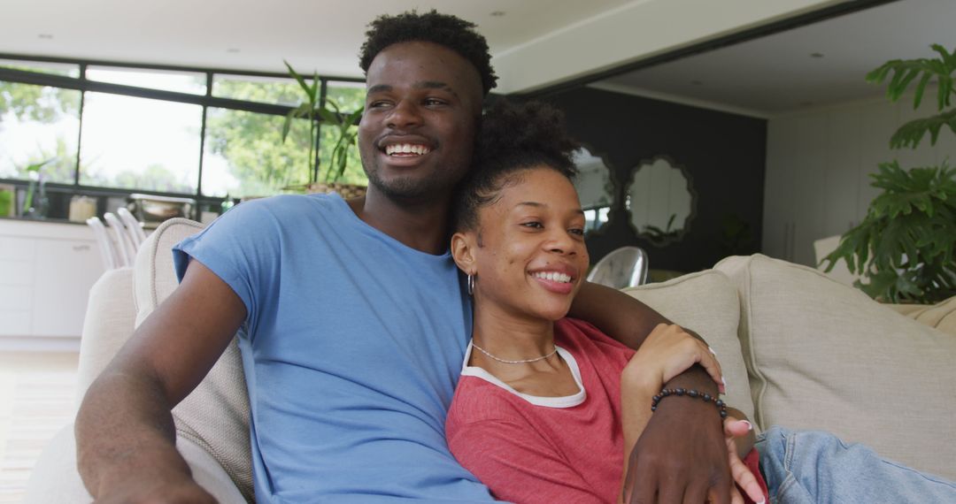 Image of happy african american couple sitting on sofa and embracing - Free Images, Stock Photos and Pictures on Pikwizard.com