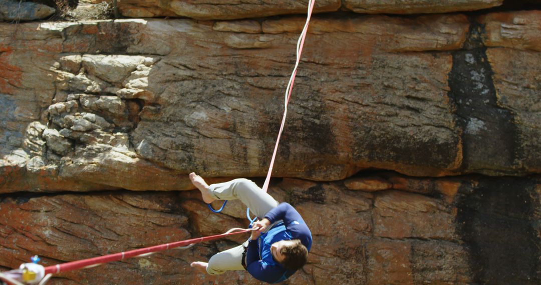 Man Climbing Rope in Front of Rocky Cliff - Free Images, Stock Photos and Pictures on Pikwizard.com