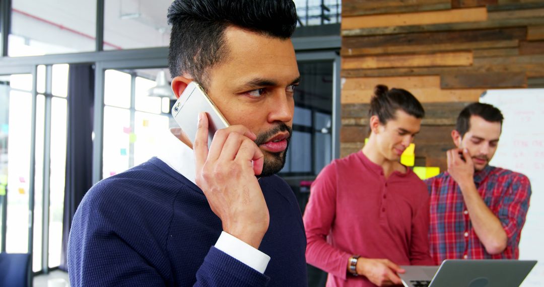 Businessman Talking on Smartphone in Modern Office with Colleagues - Free Images, Stock Photos and Pictures on Pikwizard.com