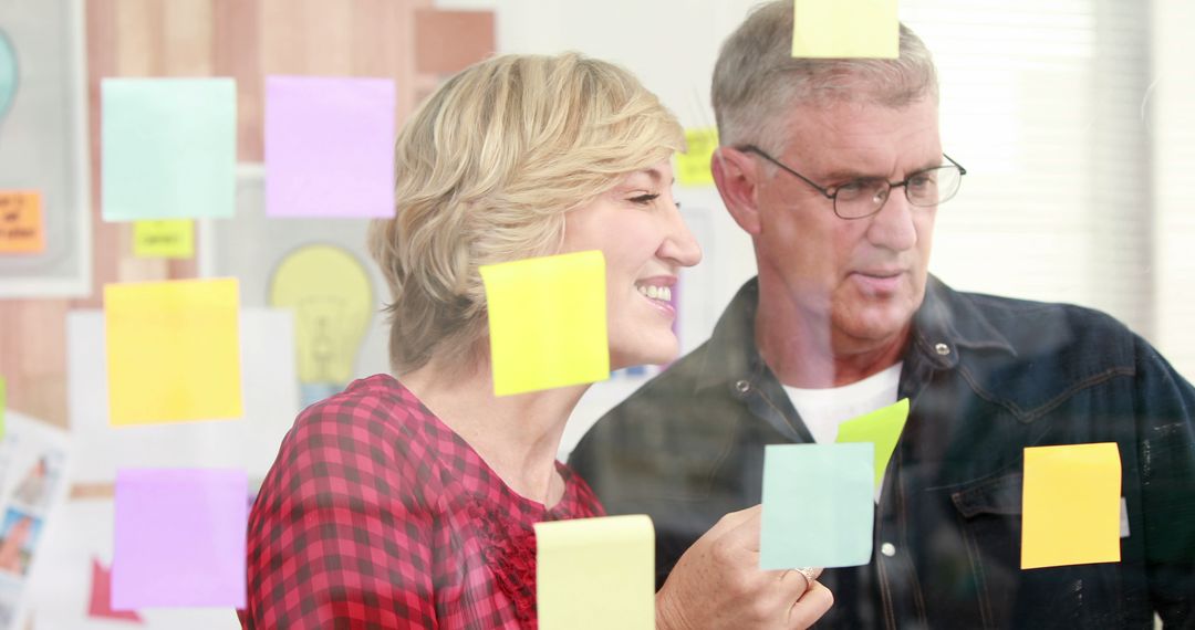 Middle-aged Colleagues Collaborating with Colorful Sticky Notes in Creative Space