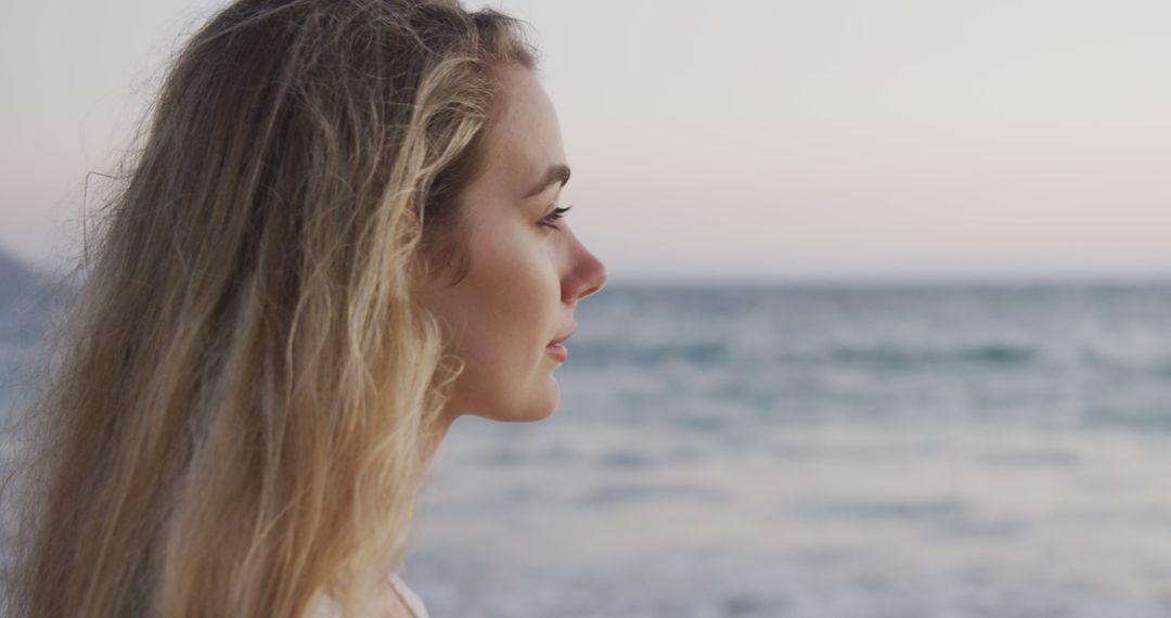 Woman With Long Blonde Hair Watching Ocean Reflectively at Sunset - Free Images, Stock Photos and Pictures on Pikwizard.com