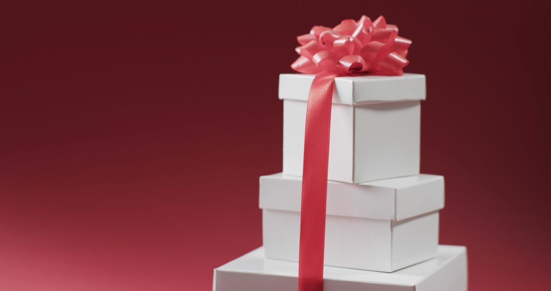 Stacked Gift Boxes with Pink Ribbon on Red Background