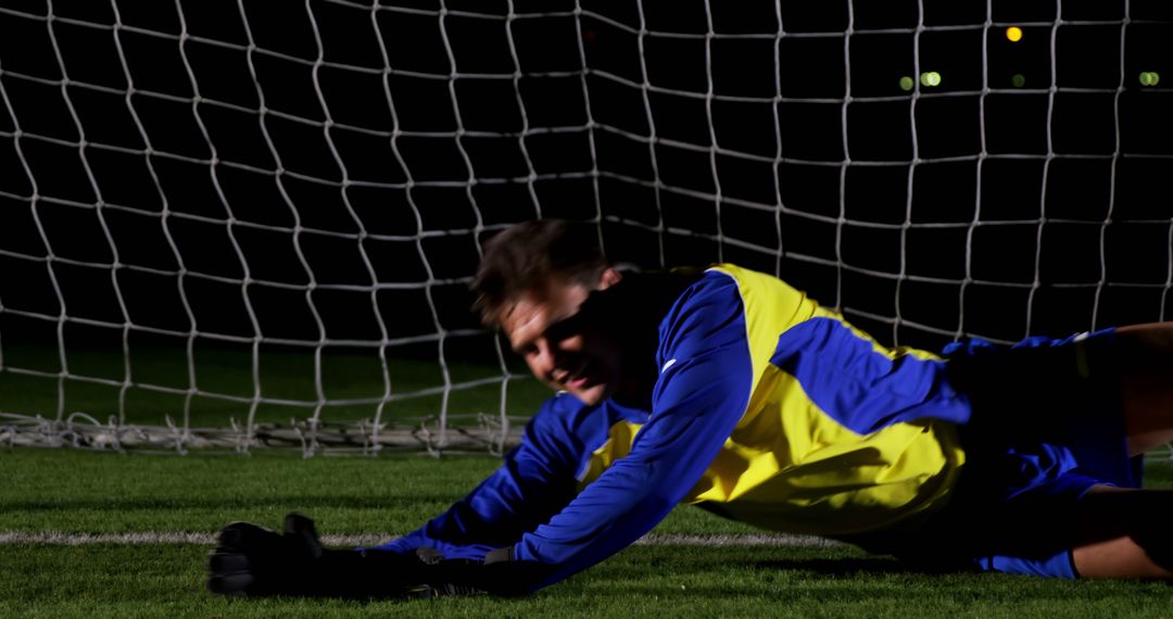 Goalkeeper diving on soccer field at night - Free Images, Stock Photos and Pictures on Pikwizard.com