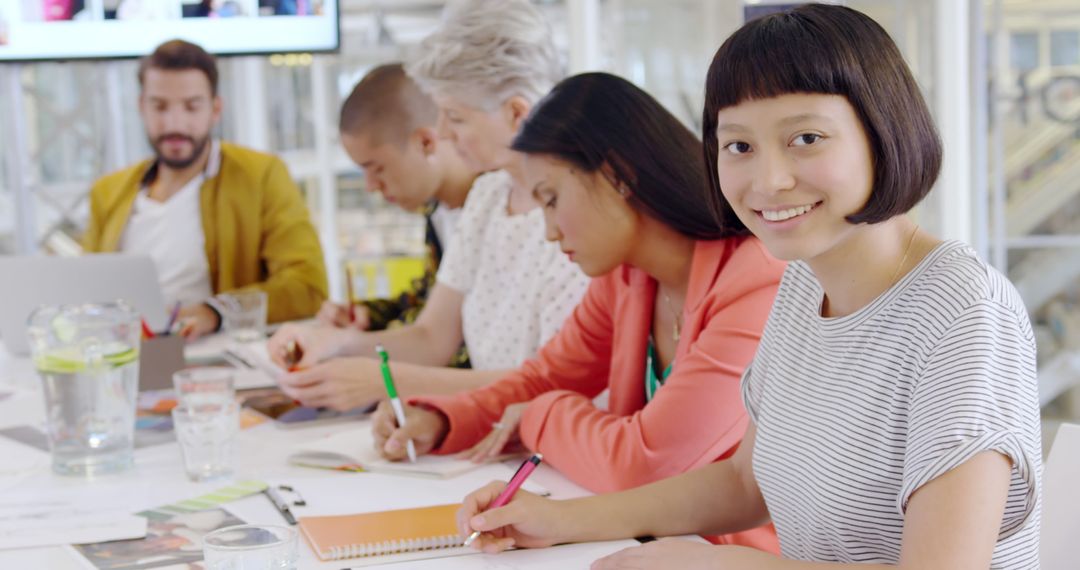 Smiling Asian Woman in Busy Collaborative Workspace