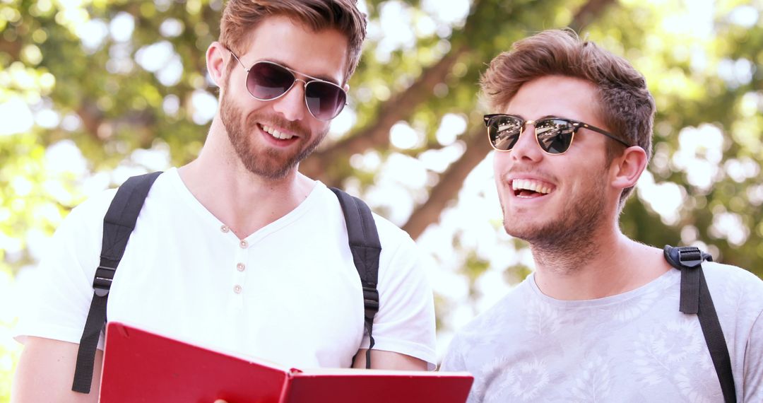 Two Young Men Smiling and Reading Outdoor in Summer - Free Images, Stock Photos and Pictures on Pikwizard.com