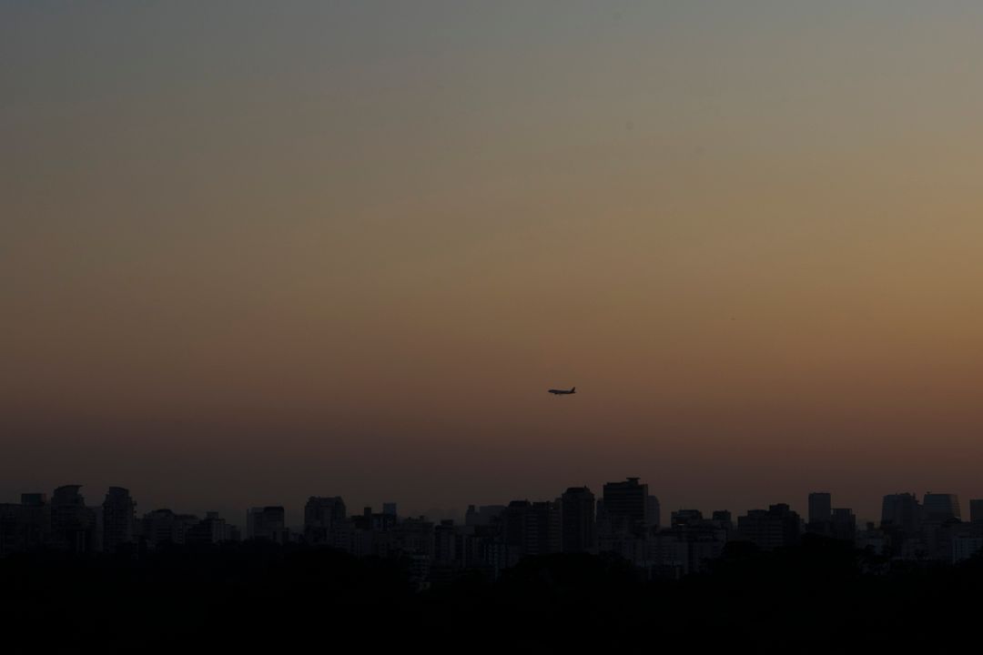 Silhouetted Airplane Flying Over City Skyline at Sunset - Free Images, Stock Photos and Pictures on Pikwizard.com