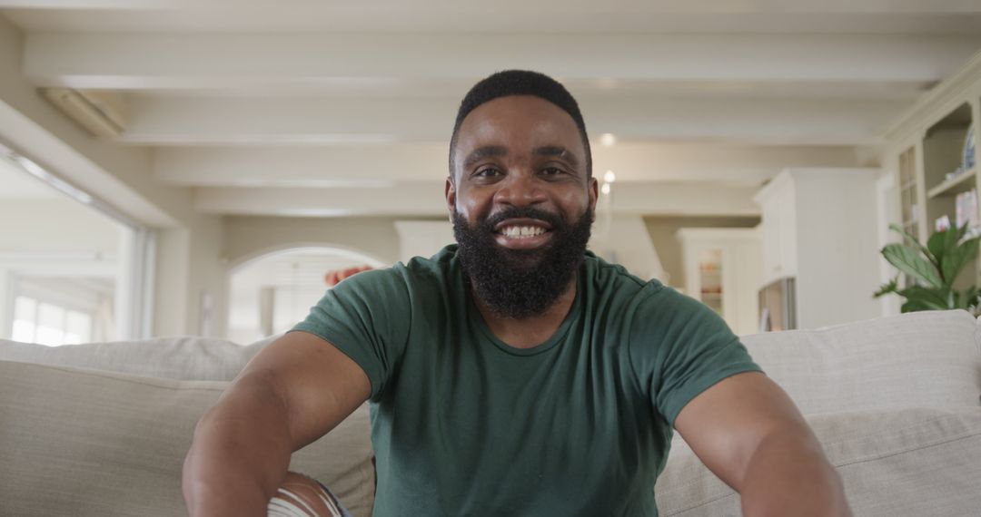 Joyful Man Enjoys Laughter on Video Call in Cozy Living Room