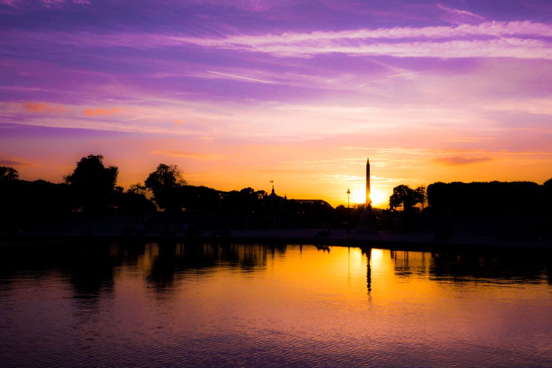 Aliomestic Sunset Over Calm Lake with Silhouetted Trees - Free Images, Stock Photos and Pictures on Pikwizard.com