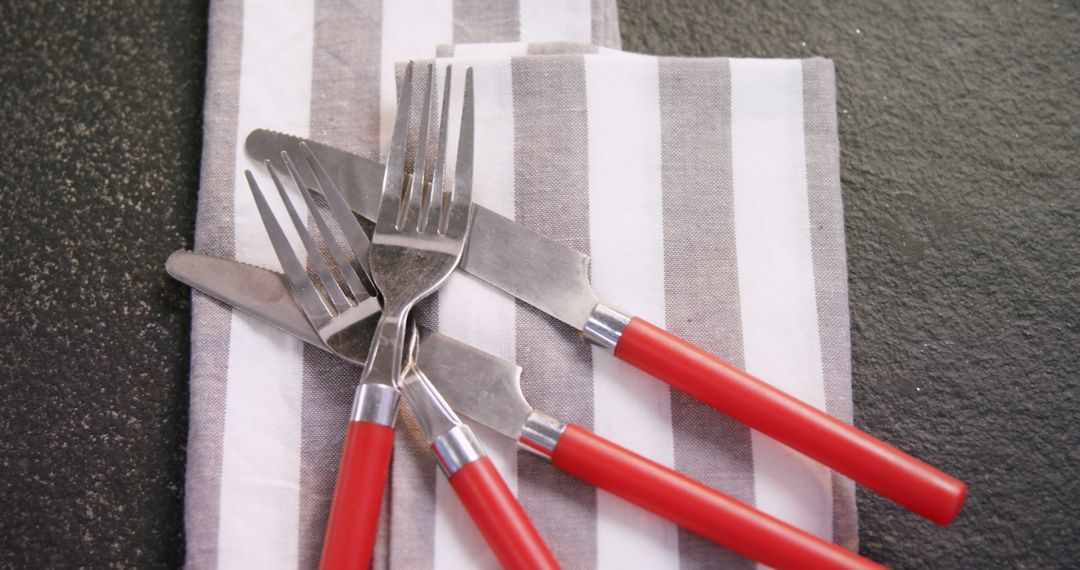 Casual Dining Cutlery with Red Handles on Striped Napkin - Free Images, Stock Photos and Pictures on Pikwizard.com