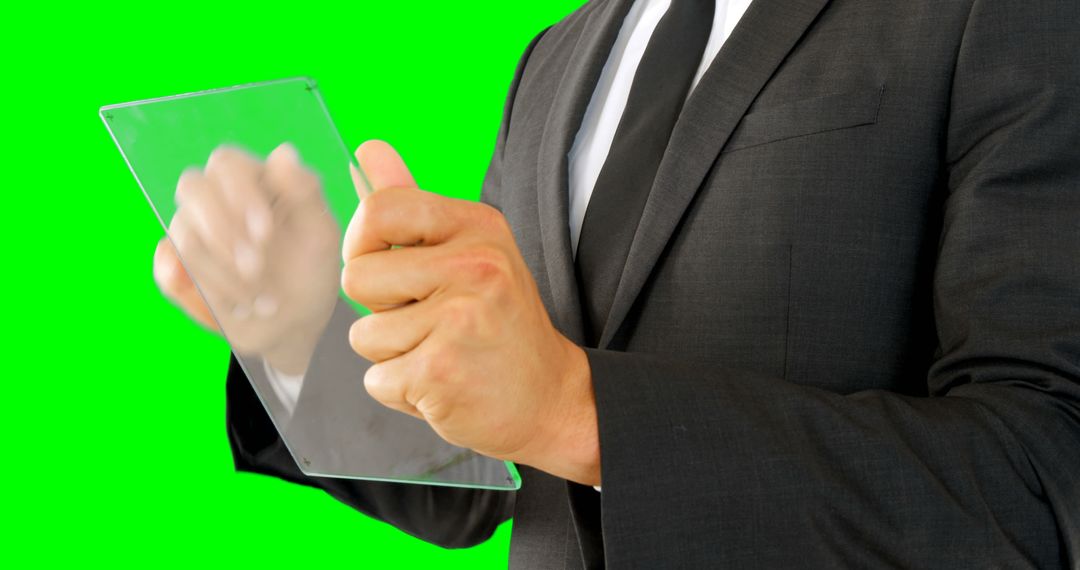 Businessman Interacting with Transparent Tablet on Green Background - Free Images, Stock Photos and Pictures on Pikwizard.com