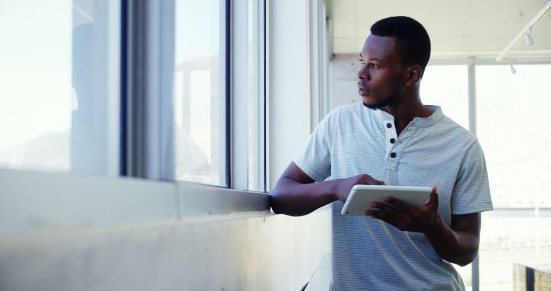 Professional Man Analyzing Data on Digital Tablet by Office Window