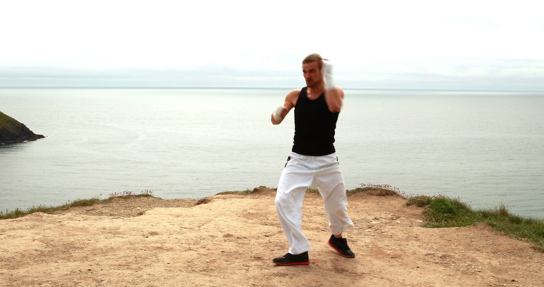 Martial Artist Practicing Moves on Coastal Cliff Edge - Free Images, Stock Photos and Pictures on Pikwizard.com