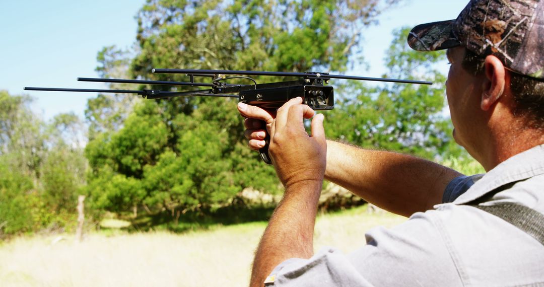 A middle-aged Caucasian man is aiming a crossbow outdoors, with copy space - Free Images, Stock Photos and Pictures on Pikwizard.com
